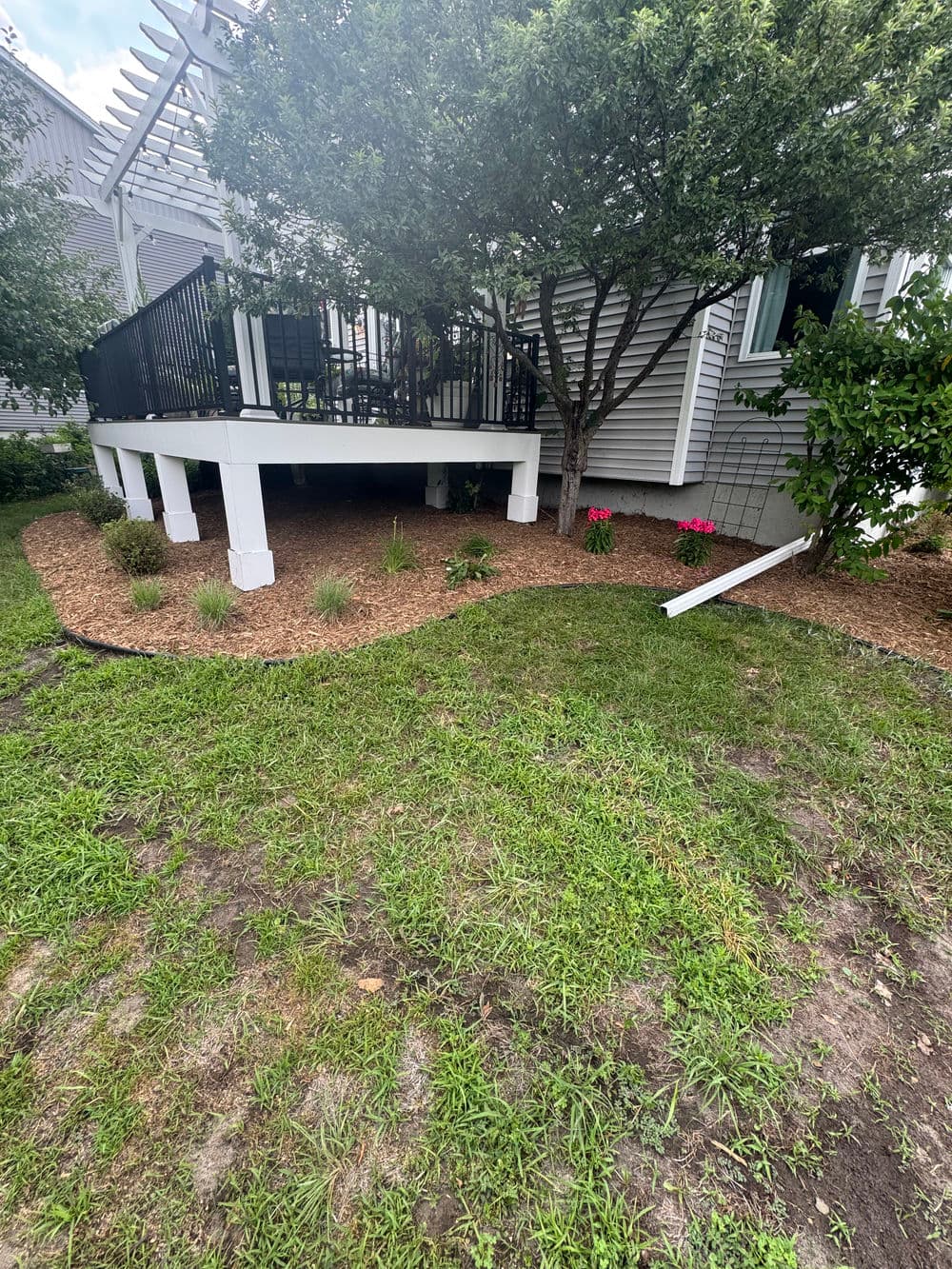 Elevated deck with black railing, surrounded by landscaped garden and colorful flowers.