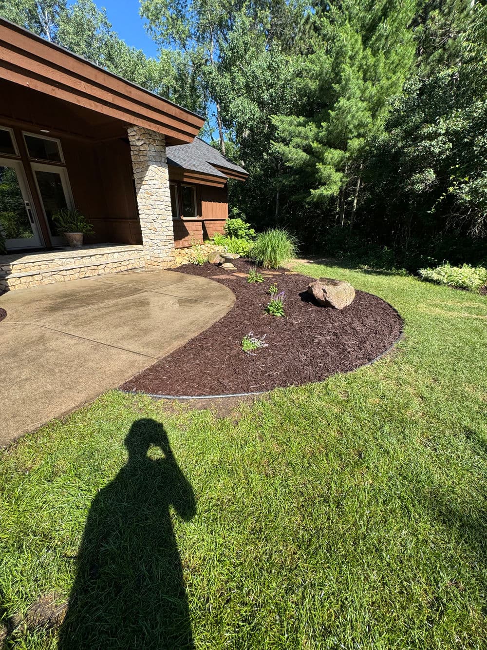 Landscaped garden with mulch, rocks, and plants near a modern home exterior.